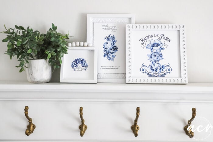 3 blue and white framed art on shelf with plant and hooks