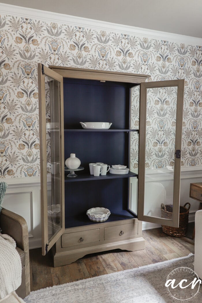 cabinet with doors open and white dishwear inside