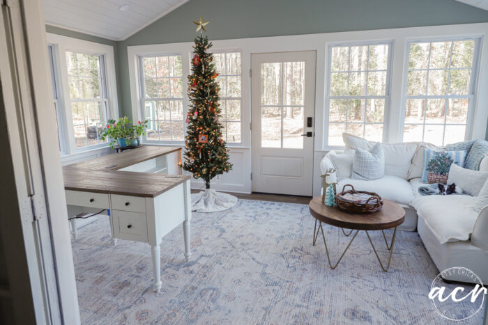 room with windows all around and tall ceiling with desks, tree and corner couch