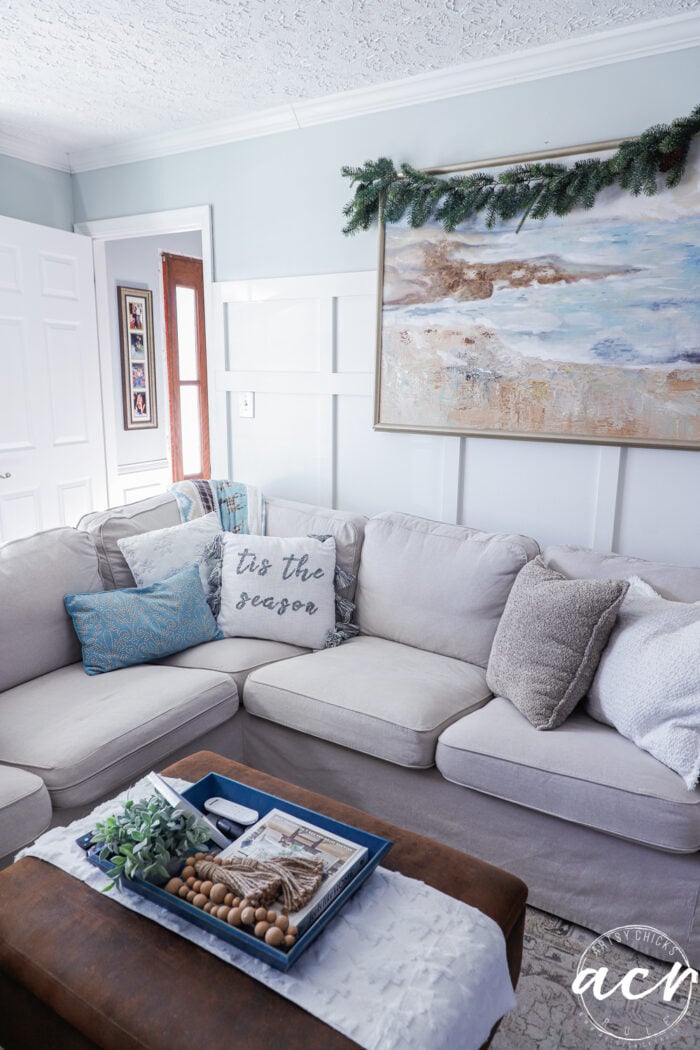 couch with christmas pillows and artwork overhead with greenery