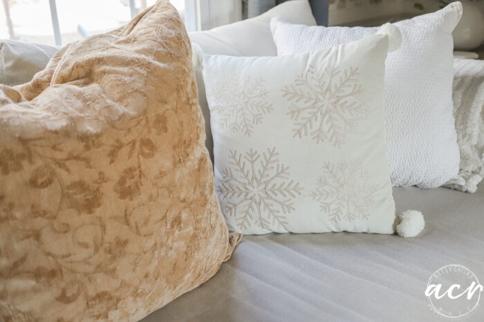 couch with mustard gold colored large pillow and snowflake pillow beside it