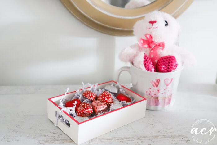 pink bear in cup with white tray and chocolate hearts