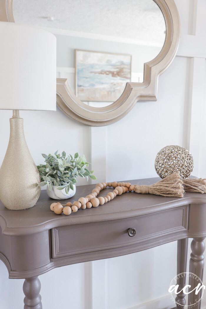up close of table top with wood beads lamp and green plant