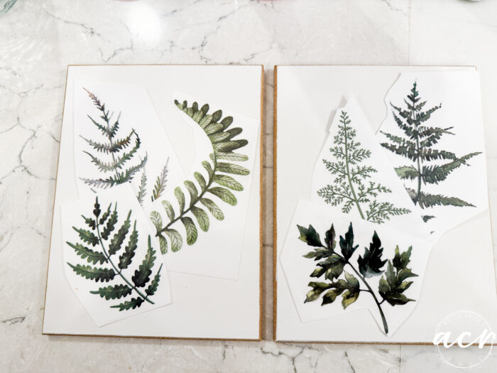 Two open sketchbooks display botanical illustrations of different fern leaves on white paper, all resting on a white marble surface. This Easter Edition artwork features a variety of green leaf shapes and textures in delightful Flipping Smalls style.