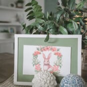 A framed illustration of a rabbit surrounded by flowers sits on a tray with a decorative white flower, a blue patterned ball, and green leaves in this cozy, softly lit room&mdash;perfect for an Easter Edition of Flipping Smalls.