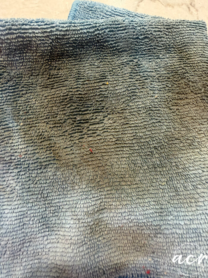 A close-up photo of a textured, blue microfiber cloth with a few small, colorful specks on its surface. Perfect for refreshing vintage furniture or giving your favorite vintage chair an easy update, the cloth is laid out flat with gentle folds.