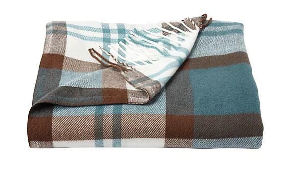A folded plaid blanket with teal, brown, and white checkered pattern, featuring fringed edges on one side—an essential addition to your Best of Fall collection.