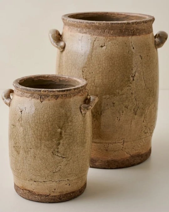 Two rustic, beige ceramic jars with crackled surfaces, each featuring two small handles near the rim, are placed side by side against a neutral background—perfect accents for your collection of Fall Favorites.
