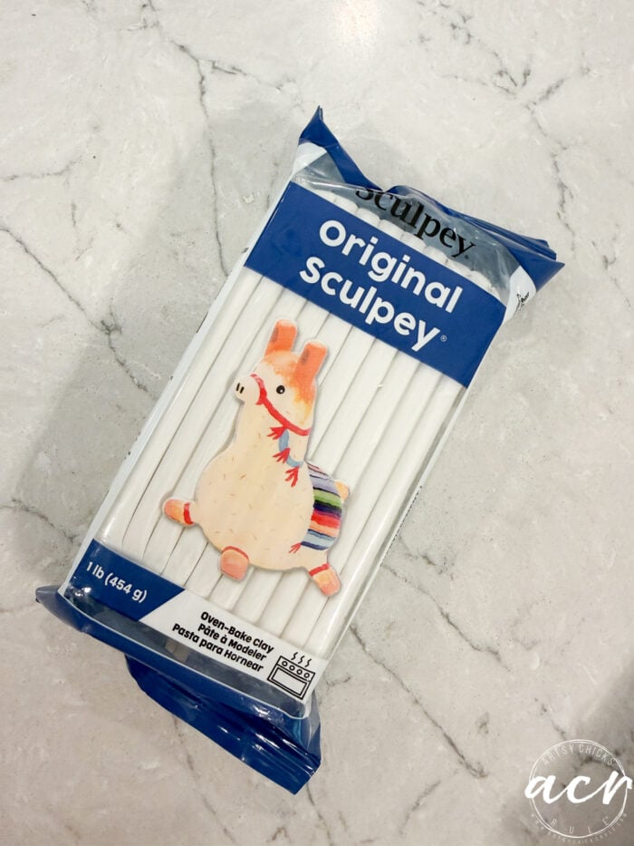 A package of Sculpey Original polymer clay with a decoration of a colorful llama on top, placed on a white marble surface—perfect for anyone interested in exploring different Air Dry Clay Brands or looking to do a creative clay comparison.