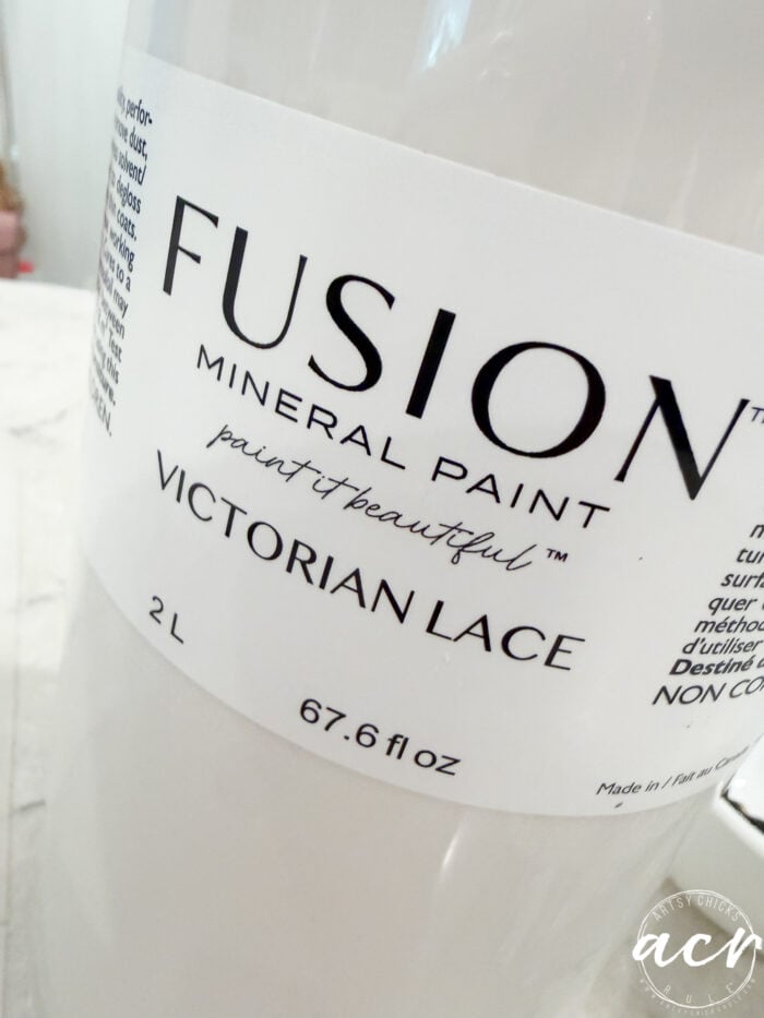 A close-up of a 2-liter container of Fusion Mineral Paint in the color Victorian Lace, with product details and Flipping Smalls branding visible on the white label.