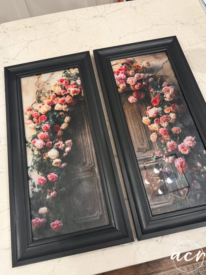 Two beautiful framed prints capture a wooden door adorned with an arch of pink, peach, and white roses, displayed side by side on a marble surface.