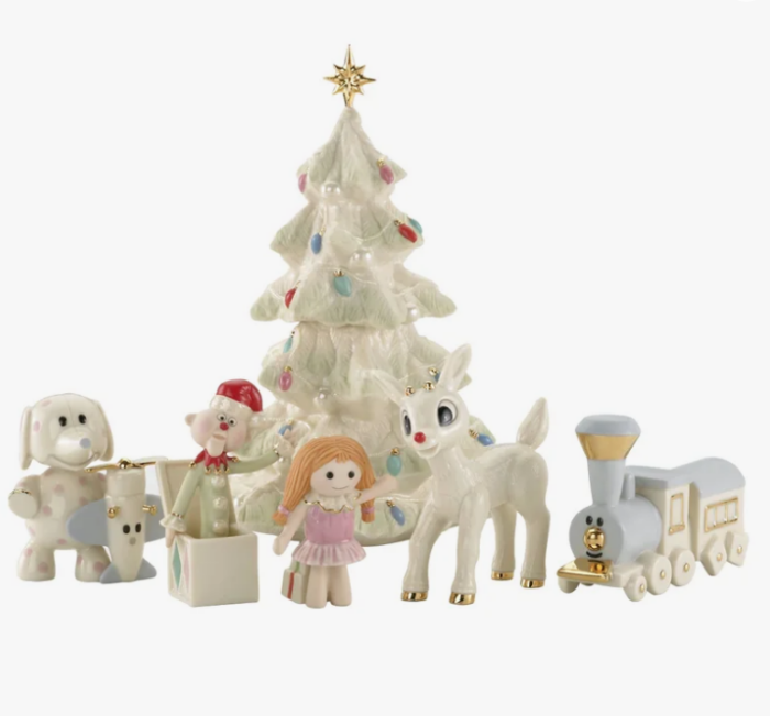 A collection of Christmas favorites ceramic figures, including a tree, a dog with an airplane, a jack-in-the-box, a girl doll, a reindeer, and a toy train.