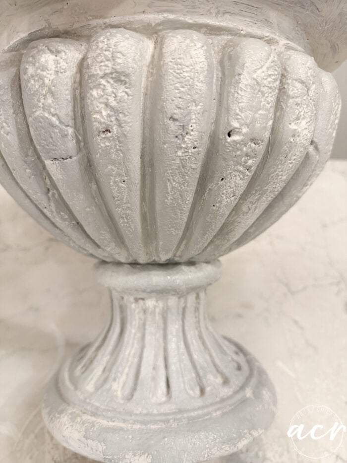 White pedestal urn with a fluted, distressed finish, styled as a DIY concrete planter.