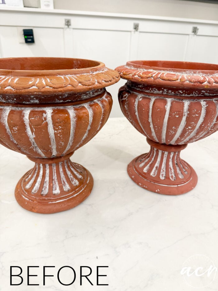 Two terracotta-colored DIY concrete planters with a decorative rim and fluted base, featuring white distressed paint accents that create a faux concrete look.