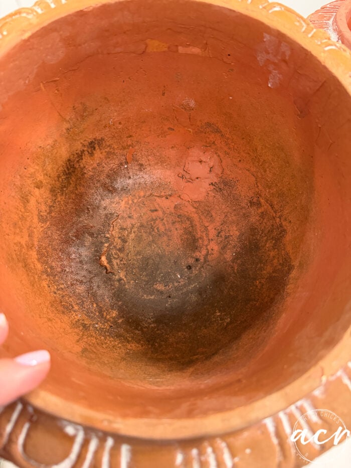 Inside a weathered terracotta pot, the DIY concrete planter tutorial aesthetic is captured through stained, textured walls.