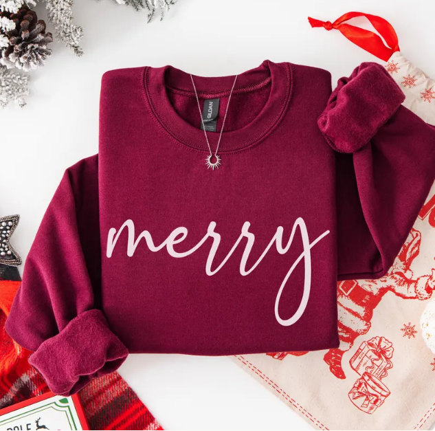 Maroon sweatshirt with the word merry written in white script across the chest, a Christmas favorite.
