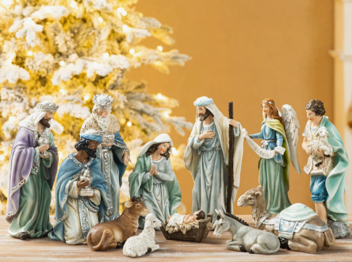 A nativity scene with figurines of the Holy Family, the Three Wise Men, an angel, and various animals in front of a lit Christmas tree, highlighting these Christmas favorites.